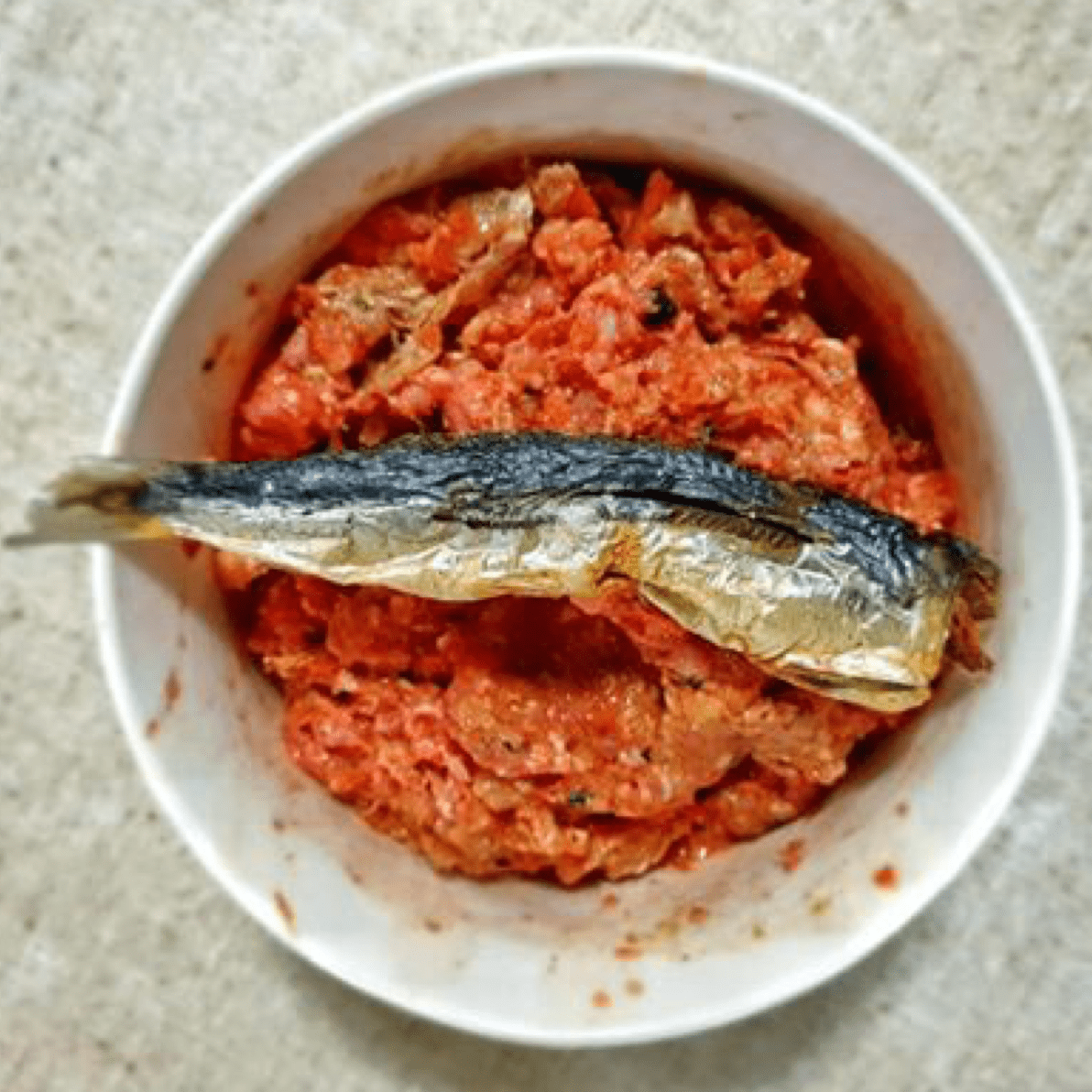 Raw dog food topped with catch of the day small oily fish